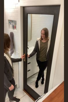 two women are standing in front of a mirror and looking at their reflection on the wall