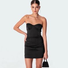 a woman in a short black dress holding a purse