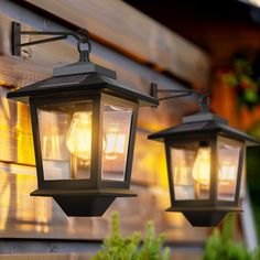 two lanterns are hanging on the side of a house, one is lit up and the other is turned on