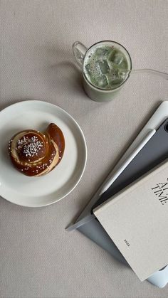 a white plate topped with a pastry next to a book