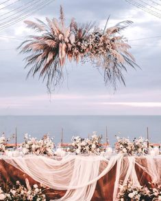 an outdoor wedding setup with flowers and greenery on the ground, overlooking the ocean