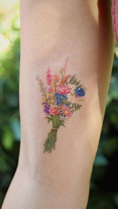 a bouquet of flowers is on the back of a woman's right arm and leg