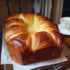 a large loaf of bread sitting on top of a table next to a cup and fork