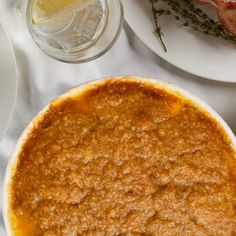 a table topped with plates filled with food next to glasses and utensils on top of a white table cloth