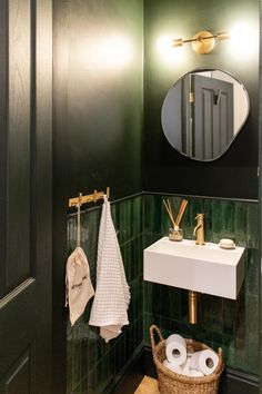 a bathroom with green tile and gold fixtures on the wall, along with a white sink