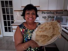 a woman holding a plate full of food in her hands with the caption paratha / buss up shot roti