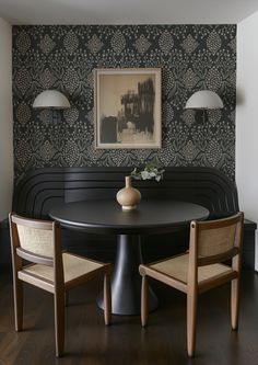 a dining room table with two chairs and a vase on the table in front of it