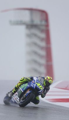 a man riding a motorcycle on top of a race track next to a tall building