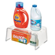 two bottles of detergent, one orange and one blue are sitting on a clear shelf