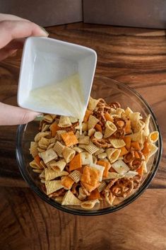 someone is pouring milk into a bowl of cheesy crackers and cheese mixture