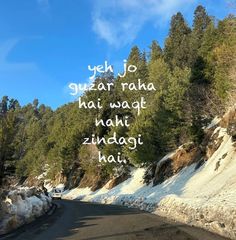 the words are written on the road in front of some snow covered hills and trees