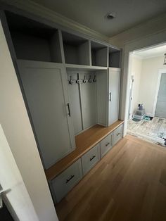 an empty walk - in closet with white cabinets and wood flooring is seen from the doorway