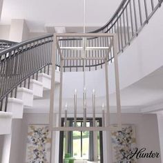 a chandelier hanging from the ceiling in a living room next to a staircase