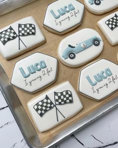 decorated cookies in the shape of race cars on a cookie sheet with words and flags