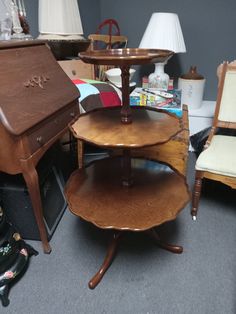 three tiered wooden table sitting on top of a carpeted floor next to a chair