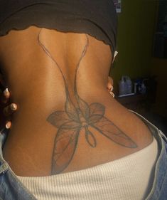 the back of a woman's lower body with a flower tattoo on her left side