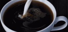 a white cup filled with black liquid and a spoon sticking out of it's side