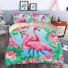 a bed with pink flamingos and tropical flowers on the comforter, next to a night stand