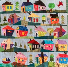 a quilted wall hanging with houses and trees