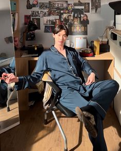 a young man sitting in an office chair with his legs crossed and hands folded out