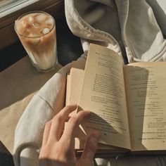 an open book sitting on top of a table next to a cup of coffee and a drink