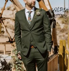 a man wearing a suit and tie standing in front of an old wooden structure with cactus plants