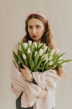 a woman holding a bouquet of white tulips