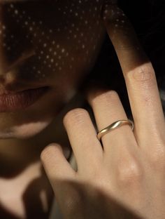 a close up of a person with a ring on their finger and her face in the background