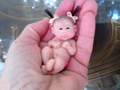 a hand holding a tiny baby doll in it's palm