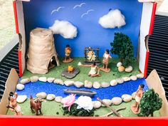 an open cardboard box filled with figurines on top of a grass covered field