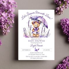 a purple teddy bear holding an umbrella on top of a white card with lavender flowers around it