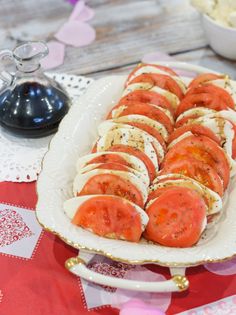 there is a platter with sliced tomatoes on it and other food items in the background