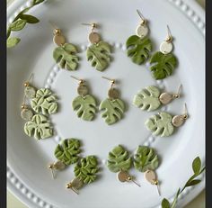 a white plate topped with lots of green leafy earrings on top of each other