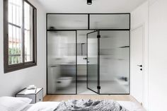 a bedroom with white walls and flooring next to a large glass door that leads into the bathroom