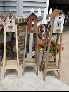 three wooden birdhouses sitting next to each other in front of a brick wall and flower pot