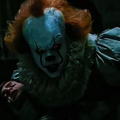 a creepy clown with red hair and blue eyes