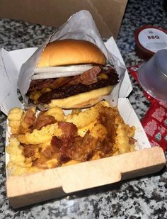 there is a sandwich and some fried food in a box on the kitchen counter top