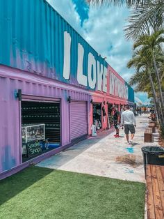 people are walking past a purple building with the words i love miami written on it