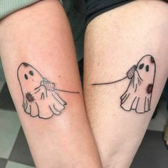 two people with matching tattoos on their legs, one holding the other's hand