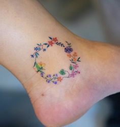 a small tattoo on the foot of a woman's foot with flowers and leaves