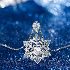 Calm, regal, and reserved, the mysterious beauty of this snowflake inspired necklace will leave you in awe. This snowflake necklace captures the beauty and intricacy of a snowflake gently falling from the sky during a winter snow. It designed is full of detailing, finished with sparkling blue sapphire stones to make it really shine on your neck. The glorious sparkle will turn heads and catch eyes. Give as a gift to someone at Christmas or treat yourself to remind you of this special time of year Blue Snowflake Sterling Silver Necklace, Silver Snowflake Necklace Elegant Style, Elegant Silver Snowflake Necklace, Elegant Christmas Snowflake Necklace, Sterling Silver Snowflake Necklace For Wedding, Mysterious Beauty, Sapphire Stones, Snow Princess, Snowflake Necklace