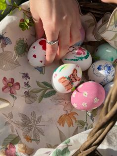 a person's hand touching an egg on a table cloth with other eggs in the background