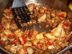 chicken and peppers cooking in a wok with a spatula on the stove top