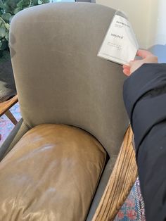 a person is holding up a piece of paper that has been placed on the back of a chair