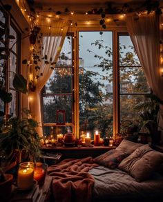 a bedroom with candles lit up on the windowsill and lights strung from the ceiling