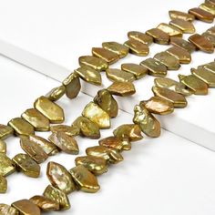 a long strand of gold colored beads on a white surface