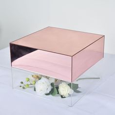 a pink and black box with flowers in it on a white tableclothed surface