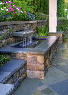 an outdoor water fountain in the middle of a stone patio with steps leading up to it