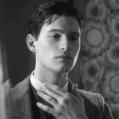 a young man is adjusting his tie in front of a mirror and looking at the camera