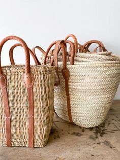 three woven baskets sitting on top of a wooden table next to an empty basket with handles